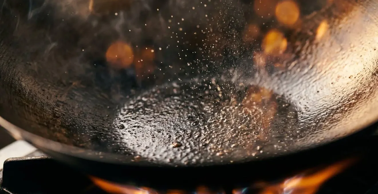 Gros plan sur la pyrolyse de l'huile dans un wok chauffé à très haute température avec des reflets de flamme